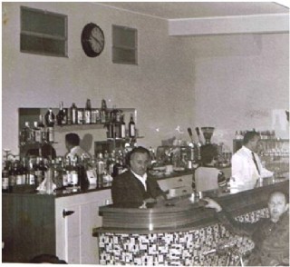 en la foto, a la derecha, con chaquetilla blanca, detrs de la barra del bar El Furacu, junto a su padre, Santos Monestina Monestina