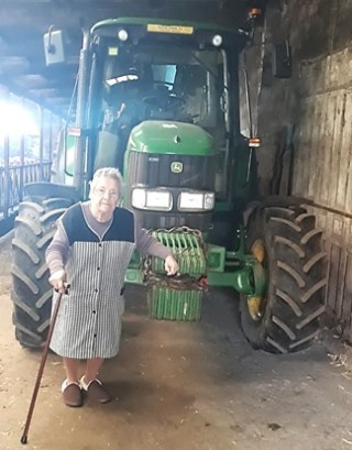 Imagen de Mara Teresa delante del un tractor en las cuadras de su propiedad