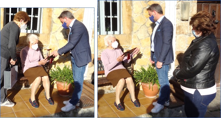 Laude recibi la placa de manos del Alcalde sentada en su amaosu bancu, a la entrada de su casa. Despus comenz a explicarse profusamente. Viriginia Naredo, en la imagen de la derecha, comparte ese momento.