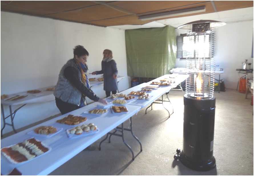 Vanessa (la duea de los kikos) coloca una bandeja de empanadillas sobre la mesa; al fondo, Orfelina, y en primer plano, la torre calefactora. / EL ECO