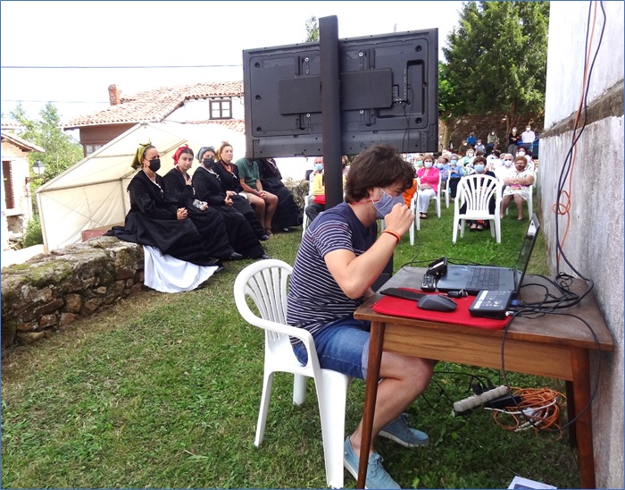 Pablo ante su ordenaor y mesa, con el monitor de espalda y devotos siguiendo la Misa por pantalla