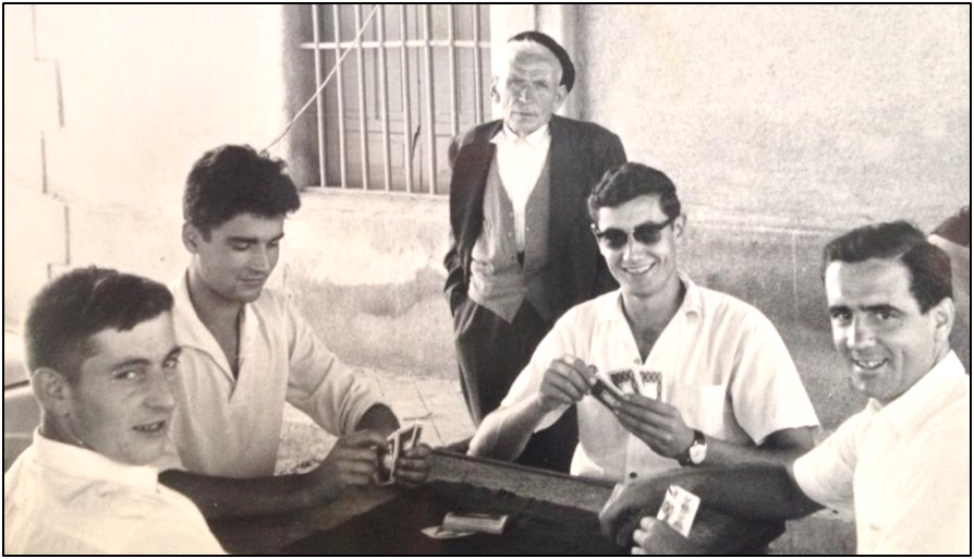 Con gafas, jugando a las cartas bajo el pláganu de la Plaza del Emigrante, en fechas próximas a su estancia en Santo Domingo, con, de izquierda a derecha, Roberto Fernández Suárez, Carlos González Llames y Alfredo Suárez Rodríguez