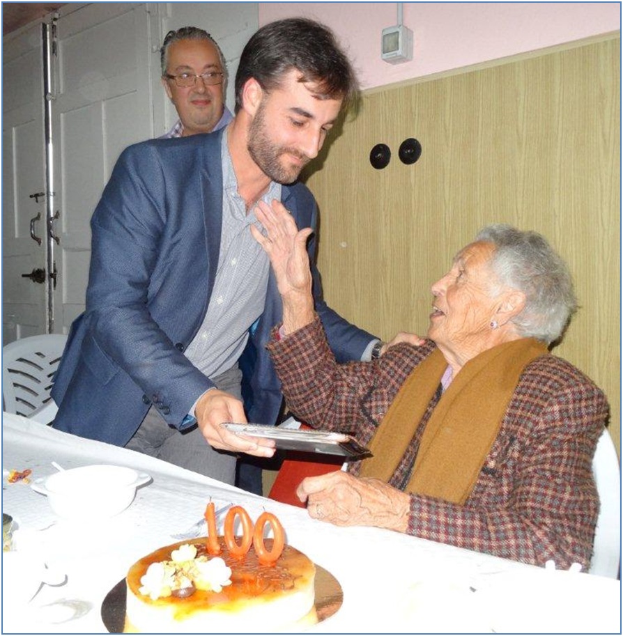 Cova recibe del Alcalde, Gerardo Fabián, la placa de todos. A la izquierda, su sobrino, Juan Ramón... y la tarta de los cien.