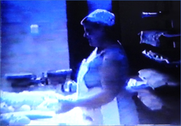 Junto a la mesa, en 1988, preparando el amasado y con panes a su espalda. | Captura del vídeo de la Asociación Cultural Incós.