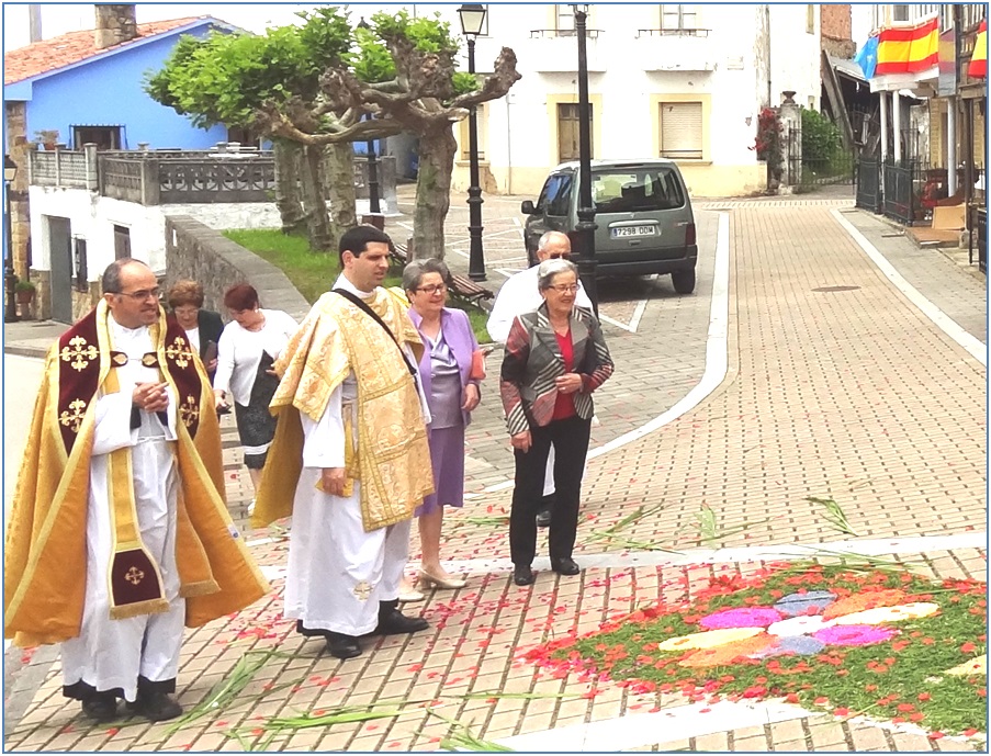 Sacerdotes y vecinos mirando las alfombras florales