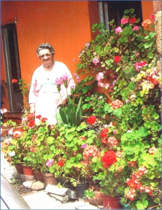 Imagen de Orfelina a las puertas de su casa, con sus amadas flores
