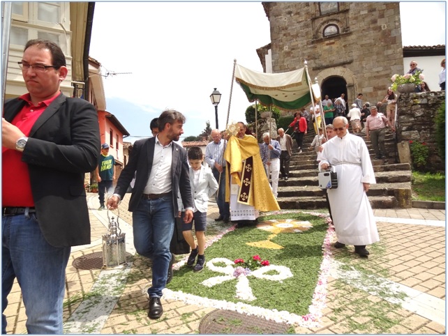 Imagen de la procesion de la Sacramental saliendo de la Iglesia y pasando sobre una alfombra floral