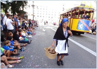 Carolina Fernández con su cesta de cucuruchos, mientras el público no para de fotografiar el tranvía. Abajo, Yaiza Alonso y Paula Villa (ésta,nieta de Amparín), ambas con la edición especial de nuestro periódico. / EL ECO